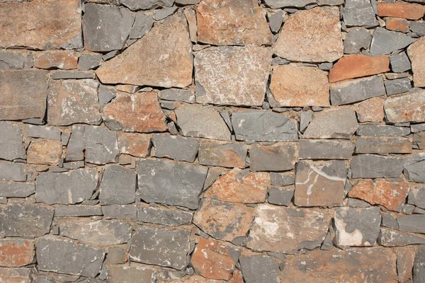 Texture of a stone. Old stone wall texture background. Grey stone wall as a background or texture. Stone wall of natural stones in different sizes. Side covering with natural stones.