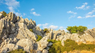 Dağlarla ve ağaçlarla kaplı bir manzara. Ağaçlı ve mavi gökyüzü olan kayalar. Yunanistan, Girit. 