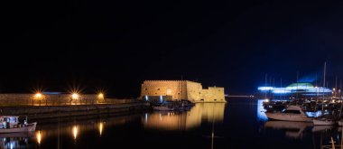 Geceleri Venedik Koules Kalesi ile Heraklion 'un eski limanının manzarası. Girit, Yunanistan. Geceleri Heraklion. Iraklion 'daki Koule Kalesi, gece.. 
