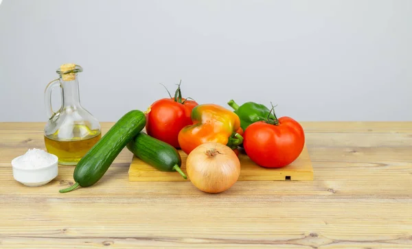 Ingredients for Greek Salad on wooden background. Vegetables on wooden background. Healthy food, Mediterranean diet. Copy space for text. Salad ingredients, tomatoes, feta, cucumber, onion, olive oil.