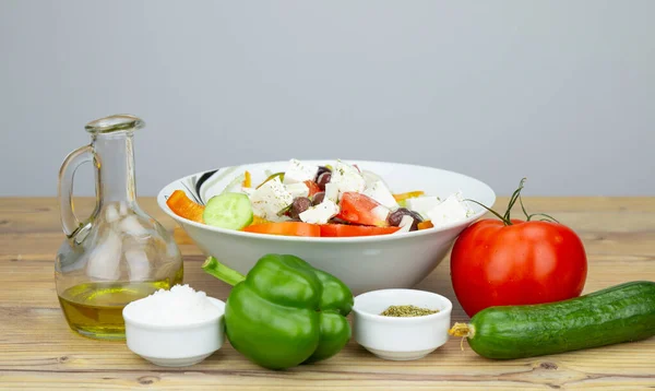 Ingredients for Greek Salad on wooden background. Greek salad with Vegetables on wooden background. Healthy food, Mediterranean diet. Salad ingredients, tomatoes, feta, cucumber, onion, olive oil.