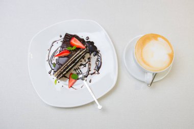 Cappuccino kahve bir fincan çikolatalı kek çilek ile dilim ile