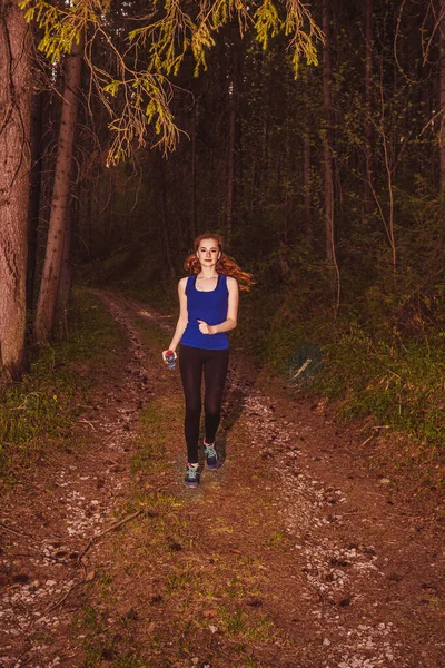 Running woman. Female runner running in dark forest.
