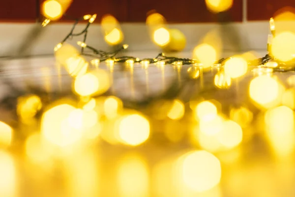 Garland glowing with warm light on floor. The atmosphere of the Christmas holidays. Overlay with golden bokeh.