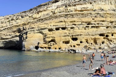Matala, Yunanistan - 07 Ekim 2018: Kum plajındaki tanımlanamayan insanlarla Tepesi'nde antik mezarlar