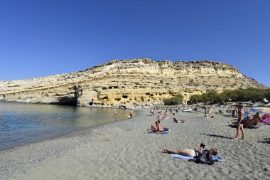 Matala, Yunanistan - 07 Ekim 2018: Kum plajındaki tanımlanamayan insanlarla Tepesi'nde antik mezarlar