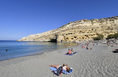 Matala, Yunanistan - 07 Ekim 2018: Kum plajındaki tanımlanamayan insanlarla Tepesi'nde antik mezarlar