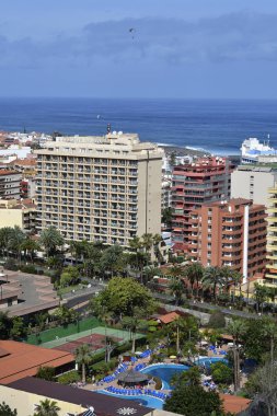 Tenerife, Kanarya Adaları, İspanya - 01 Nisan 2018: cityscape farklı binalar, Otel havuzu ve Tenis Kortu Puerto de la Cruz'da Atlantik Okyanusu üzerinde gökyüzünde para planör ile