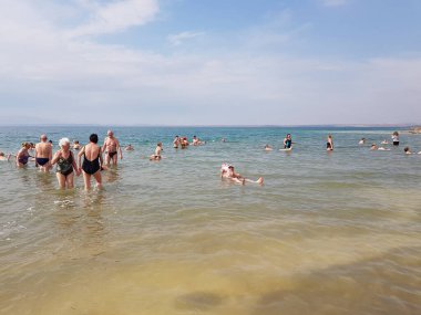 Akabe, Ürdün - 05 Mart 2019: Kimliği belirlenemeyen insanlar Ölü Deniz 'de banyo yapıyor, Ölü Deniz' de yüzebiliyorsunuz ama suya giremiyorsunuz çünkü tuz miktarı çok yüksek.