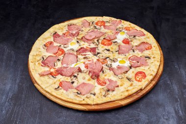 Pastırmalı ve yumurtalı Carbonara pizzası güzel gri masada. Koyu arkaplanda izole.