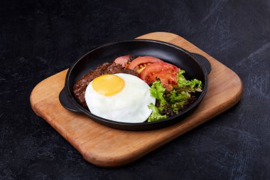 Tavada yumurta, dilimlenmiş domates, salata ve pirzola.