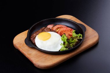 Tavada yumurta, dilimlenmiş domates, salata ve pirzola.