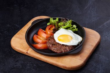 Tavada yumurta, dilimlenmiş domates, salata ve pirzola.