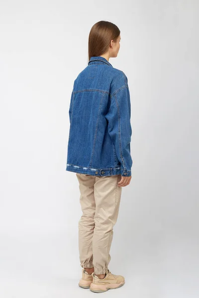 Девушка в бежевых штанах и джинсовой куртке . — стоковое фото