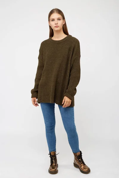 Flicka klädd i en khaki tröja och jeans. — Stockfoto