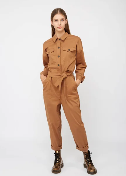 Girl in camel color jumpsuit on white backround.