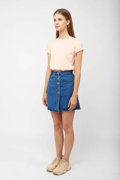 Teenager girl in a denim blue skirt on a white background. — Stock Photo, Image