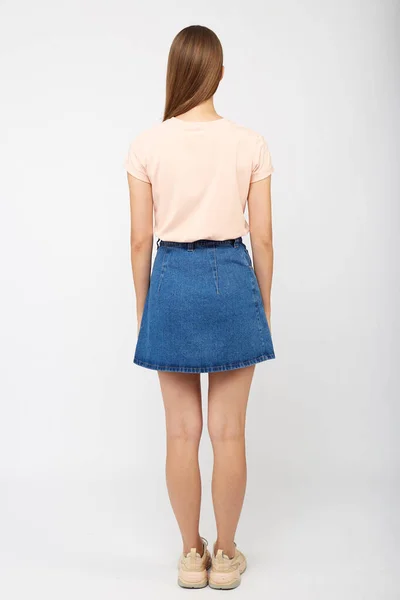 Teenager dívka v džínové modré sukni na bílém pozadí. — Stock fotografie