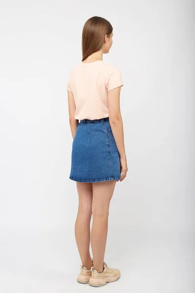 Tonårstjej i jeansblå kjol på vit bakgrund. — Stockfoto