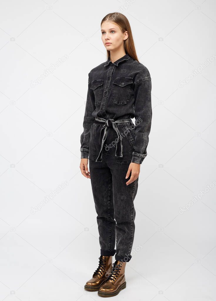 Girl in black denim jumpsuit on white background.