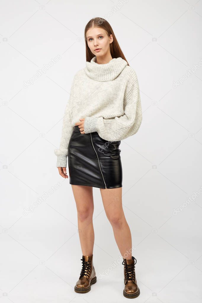 A girl dressed in a white sweater and a black eco-leather skirt
