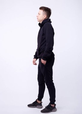 Siyah kapüşonlu, elleri ceplerinde duran yakışıklı ve ciddi bir gencin izole edilmiş portresi. Hackleme ve moda kavramı