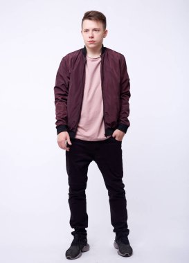 Kot pantolonlu genç adam, beyaz arka planda parlak naylon bordo bombacı ceketi..