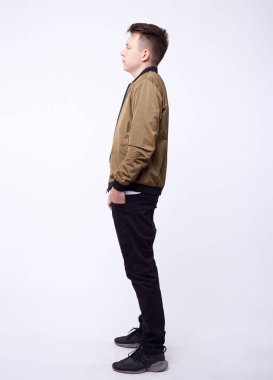 Kot pantolonlu genç bir adam, beyaz arka planda parlak naylon bir bombacı ceketi..