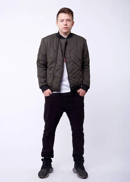 Jovem de jeans, jaqueta de nylon brilhante cinza bombardeiro no fundo branco . — Fotografia de Stock