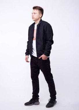 Kot pantolonlu genç adam, beyaz arka planda siyah bombacı ceketi..