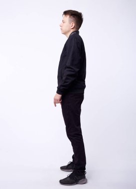 Kot pantolonlu genç adam, beyaz arka planda siyah bombacı ceketi..