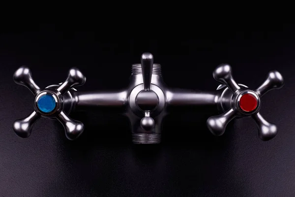 Bath mixer, tap close up. Black background. Faucet handle with cold water close up.