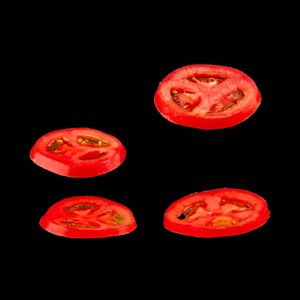 Tomate voador. Tomate vermelho fatiado isolado sobre fundo preto. Levidade vegetal flutuando no ar . — Fotografia de Stock