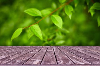 Modelleme. Yaprak bokeh arkaplanlı boş ahşap güverte masası.