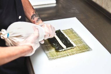 Beyaz arkaplanda suşi yapma süreci