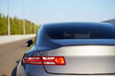 Yazın güneşli bir günde, arka pencereye park etmiş gri bir araba. Çıkartma veya çıkartma için modelleme