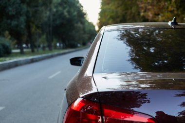 Kahverengi arabanın arka camı sokağa park edilmiş..