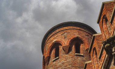Yuvarlak kule ve bulutlu bir gökyüzüne karşı bir tuğla duvarın parçası