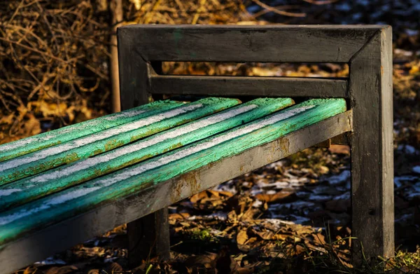 Old park bench with first snow on the boards