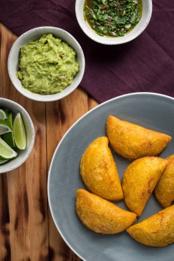 Bir tabakta aji (acı sos), yanında tuz ve guacamole bulunan Empanadas (ciro)