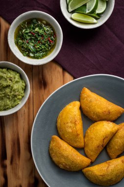 Bir tabakta aji (acı sos), yanında tuz ve guacamole bulunan Empanadas (ciro)