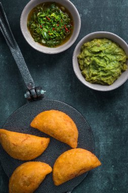 Acılı soslu tortilla presörünün üzerinde Empanadas (ciro), yanında tuz ve guacamole