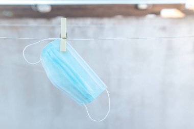 Çamaşır ipinde mandalla asılı olan koronavirüs için cerrahi mavi maske. Dezenfekte için temiz maske. Tekrar kullan. Covid-19. Boşluğu kopyala.