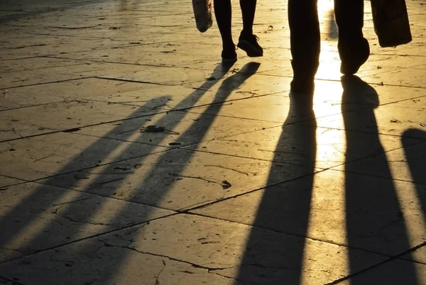 Gün batımında kaldırımda bacak gölgeleri