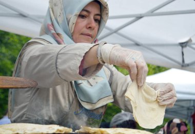 Bükreş, Romanya. 22 Mayıs 2016. Bükreş'teki Türk Festivali'nde, saj fırınında geleneksel yassı ekmeğin pişirme sürecini türk kadını üst üste bindiriyor,