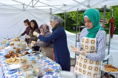 Bükreş, Romanya. 22 Mayıs 2016. Güzel genç Türk kadını Bükreş'teki Türk Festivali'nde geleneksel yemekler servis ettikten sonra eldivenli ellerine bakıyor 