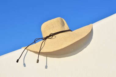 Beyaz duvardaki hasır şapka ve gökyüzü arkaplanı