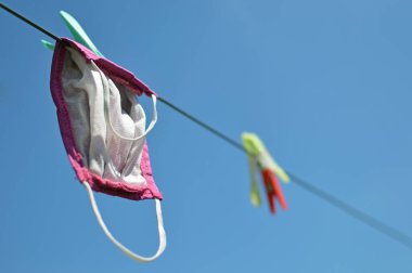 Yeniden kullanılabilir kumaş maske çamaşır ipinde güneşte asılı.