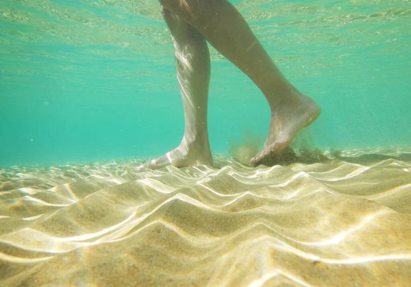 Underwater shot of male legs walking on sea bottom