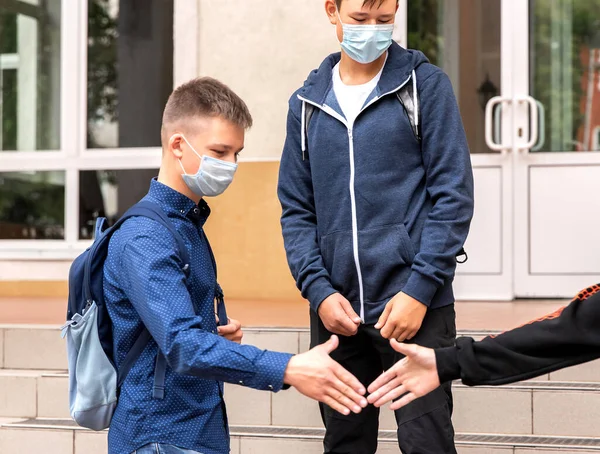 Tres amigos de la escuela se saludan en el patio del colegio. —  Fotos de Stock